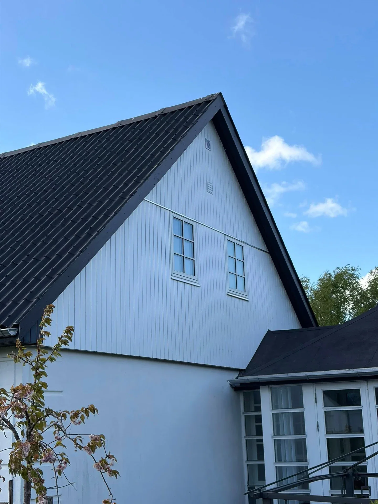 Moderne hus med sort tag og hvid facade, klar til nybyggeri eller renovering.