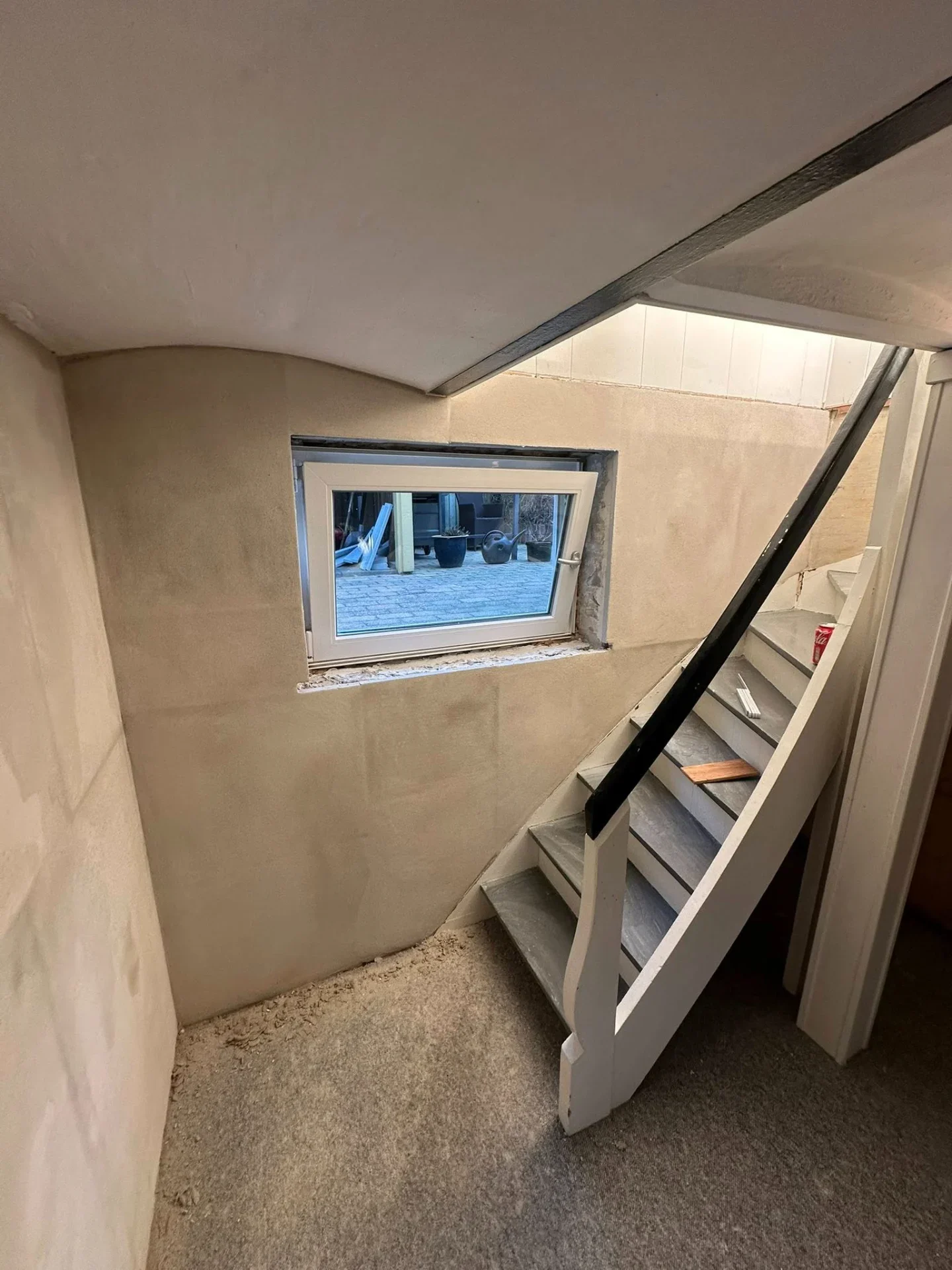 Billedet viser en trappe under renovering med ny væg- og vinduesinstallation.